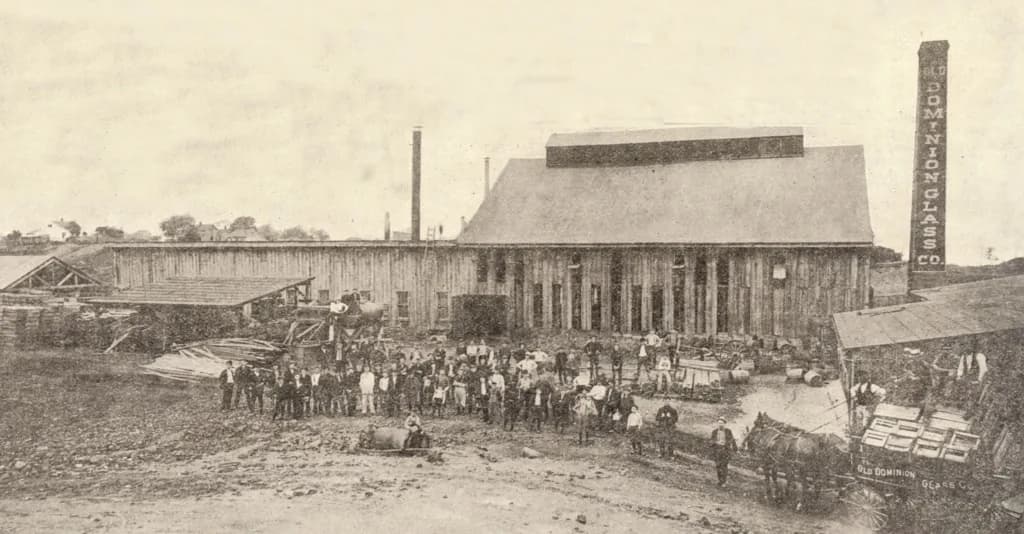 An old black-and-white photograph of workers in front of a factory
